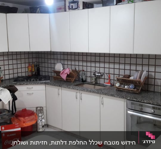 מטבח עם ארונות לבנים, כיור, ותנור אפייה